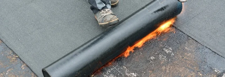 Person bringt Dachpappe mit Gasbrenner an